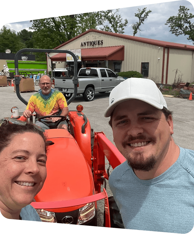People posing with a tractor at antiques shop.